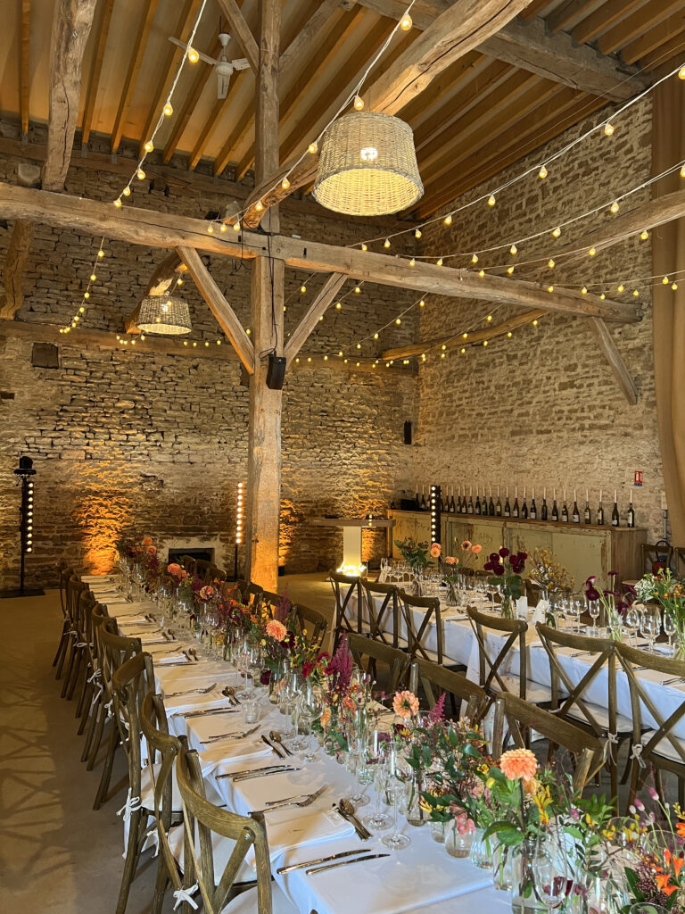 salle de mariage avec pierre et poutre, lumière guirlande et beaucoup de fleurs colorées