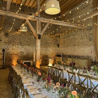 salle de mariage avec pierre et poutre, lumière guirlande et beaucoup de fleurs colorées