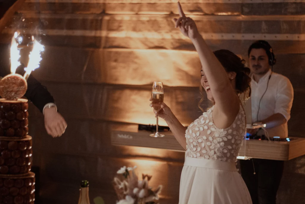 mariée heureuse qui lève sa flute de champagne devant sa pièce montée à son mariage